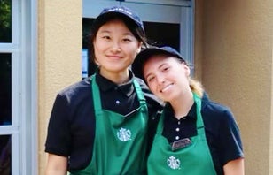 Two smiling dining employees in front of Starbcucks.