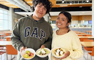 Two smiling UCI students holding bowls of Beef Donners in their hands.