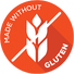 A circular vibrant orange icon displaying a white wheat stalk crossed out by a diagonal slash, with the text "MADE WITHOUT" along the upper left edge and "GLUTEN" along the lower right edge.