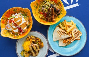 Image with four bowls and plates of food from the dining hall on a blue tablecloth.
