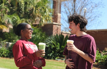 students laughing and drinking coffee in front of fsu student union