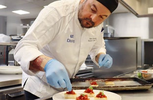 a UC Irvine Dining chef placing garnish on top of dessert.