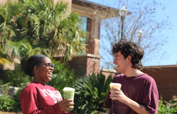 students sit outside the student union on a bench
