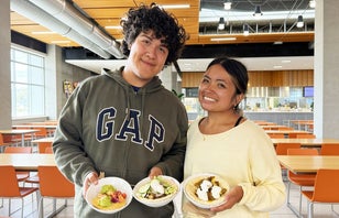 Two smiling UCI students holding bowls of Beef Donners in their hands.