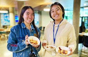 Two smiling UCI students holding theirs plates full of food.