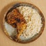 A top-down view of a seasoned, roasted chicken leg served alongside a portion of white rice on a speckled ceramic plate.
