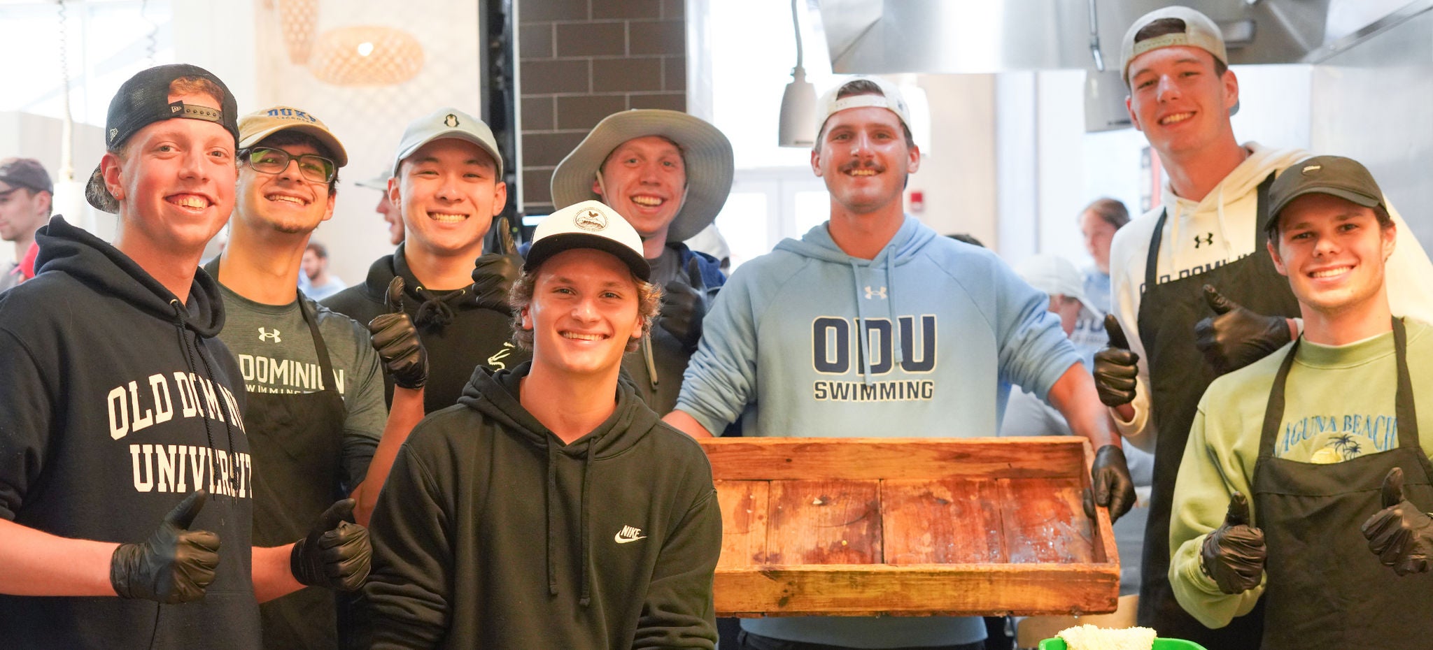 8 students posing in Broderick Dining Commons during a cooking class.