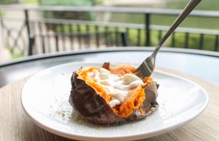 a sweet potato with marshmallow on a white plate with a fork