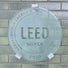 A circular glass plaque mounted on a green brick wall in the Malkin Sacks Commons, etched with the "LEED Silver 2020" logo for Leadership in Energy and Environmental Design.




